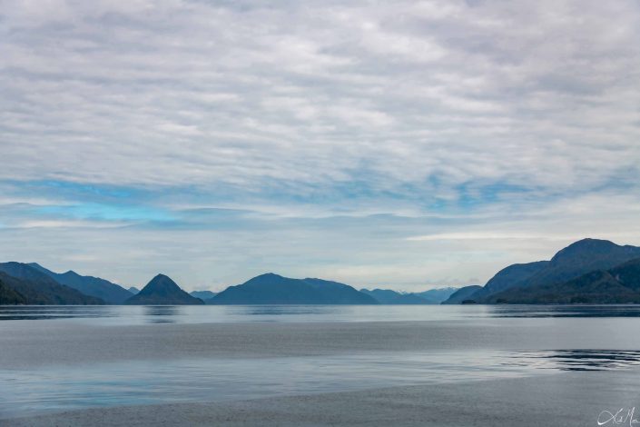 Beautiful shades of blue in the sky and the water below, with silhouette of the mountains in the middle