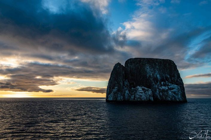 Scenic photo at sunset of a rock in the middle of the sea in Galapagos