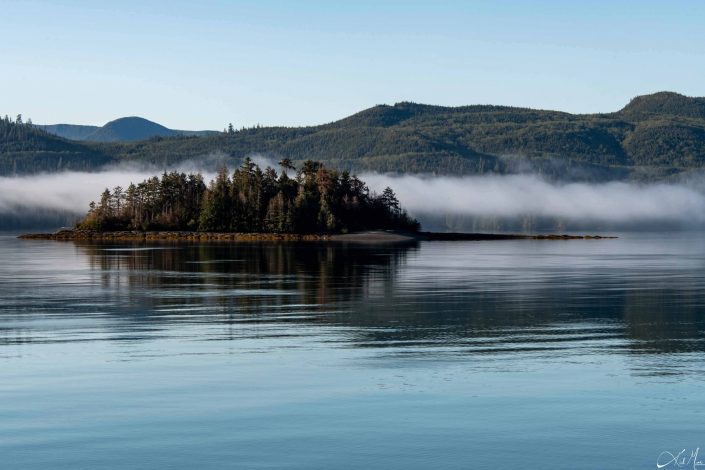 Beautiful scenic photo with fog close to the waters, and beautiful shades of blue in the sky and water along with mountains in the background