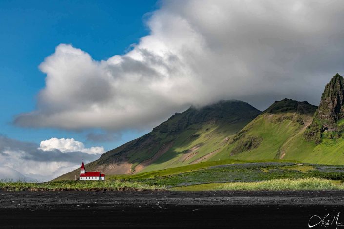 Scenic photo of a church/ cathedral. Beautiful photo of the black sandy beach with fresh green mountain and bright blue sky