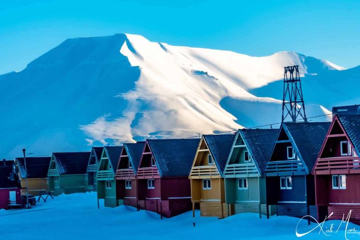 Best scenic photo of colourful houses in Longyearbyen with snow covered mountain behind it.