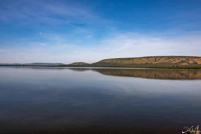 Beautiful picture of the lake with mountains in the background and you can see a clear reflection of the mountains on the lake waters.