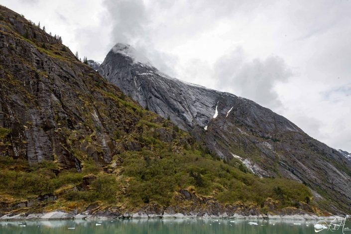 Green-grey mountains along with green water in the front