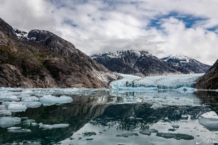 Scenic photo of mountains with a glacier and a clear reflection of it in the water in the front