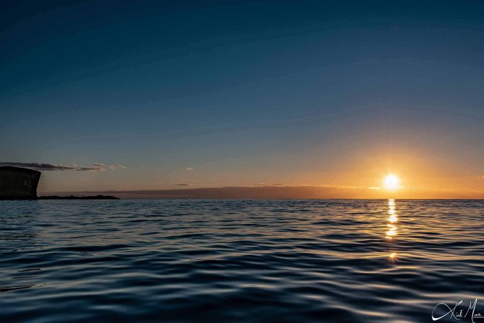 Best sunrise photo with dreamy blue waters in the foreground and the sun shinning like a diamond with its reflection and hues in the waters below