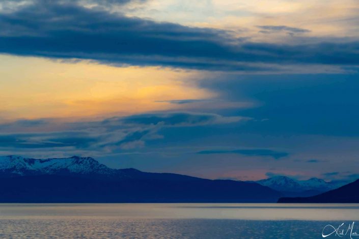 Scenic sunset with snow-capped mountains and silvery water