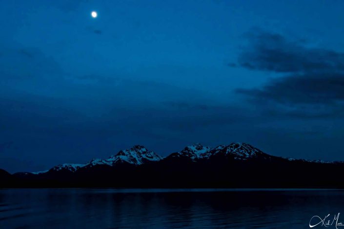 Beautiful sunset with dark shades of blue with snow-capped mountains and moon