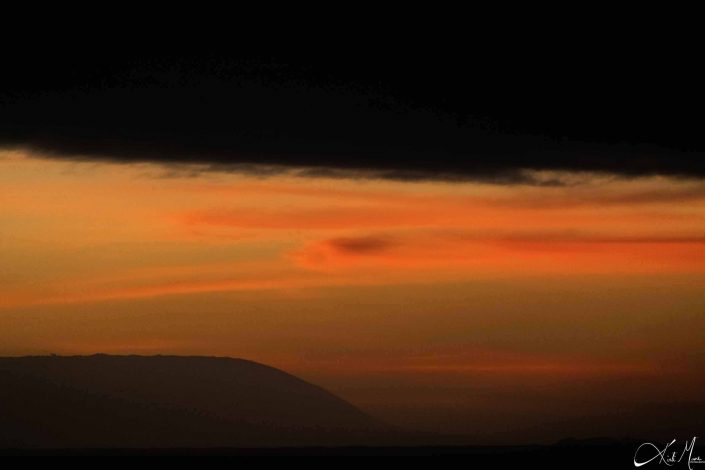 Beautiful sunset with dark mountain in the background and shades of orange, yellow and pink in the sky