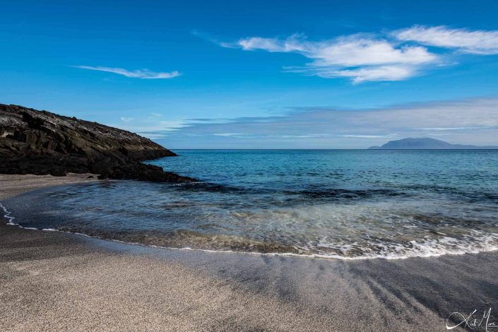 Beautiful beach with turquoise waters, blue sky and a mountain in the background