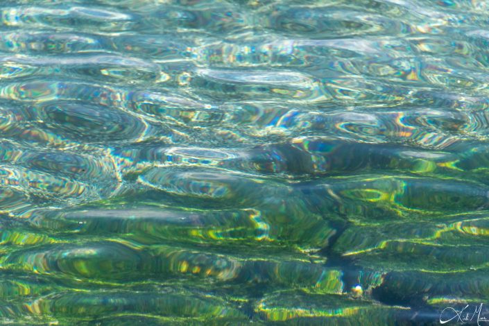 Close up of sea water with shades of green and rainbow colored hues