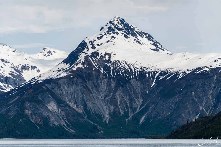 Beautiful photo of a dark grey-black mountain with a snow cap