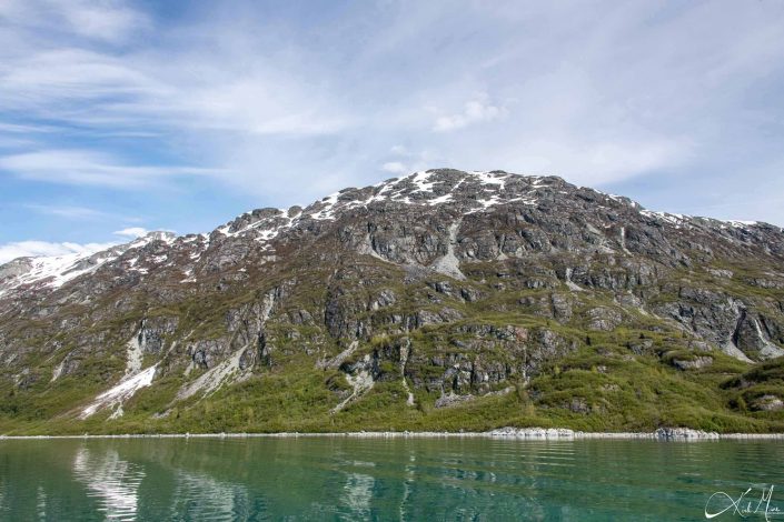 Beautiful photo of a grey-green mountain with green/ emerald waters in the front