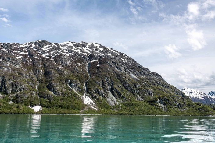 Beautiful photo of a grey-green mountain with green/ emerald waters in the front