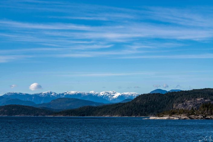 Beautiful photo of blue waters and brilliant blue sky above, with mountains in the background