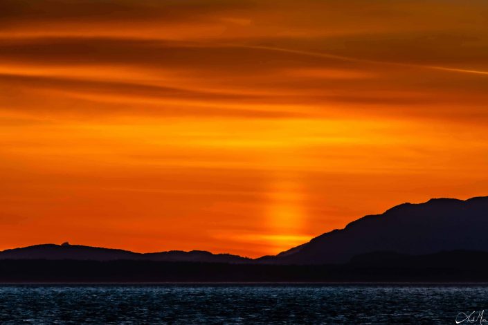 Best sunset photo with orange golden hues, deep shades of blue on the waters and silhouette of the mountains in the background