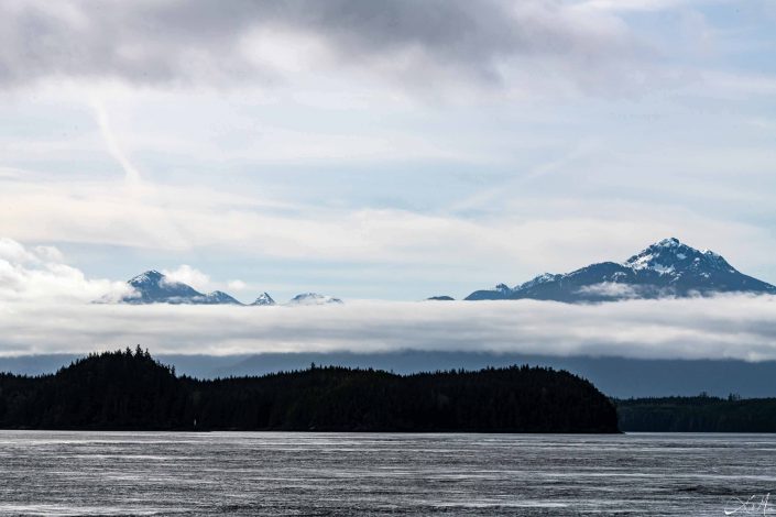 Scenic photo of a strip of fog between the mountains and the sea