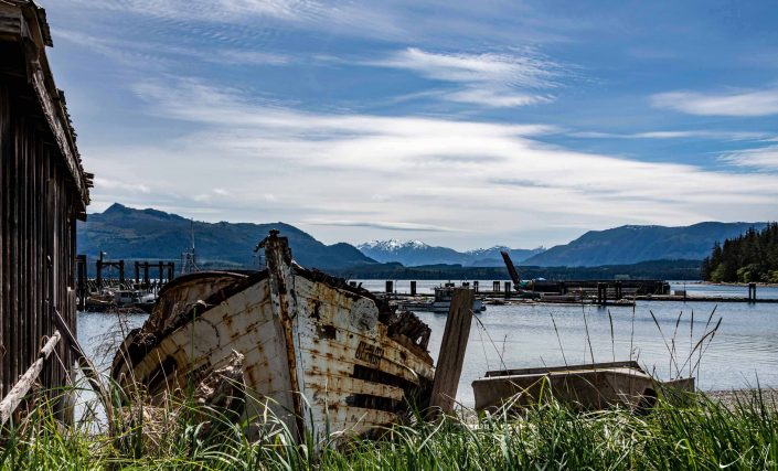 Artistic photo with rusty boat on the beach and beautiful shades of blue seen in the waters and sky with snow capped mountains in the background